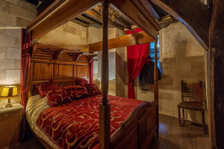 Le baldaquin — Un lit sculpté sous les poutres